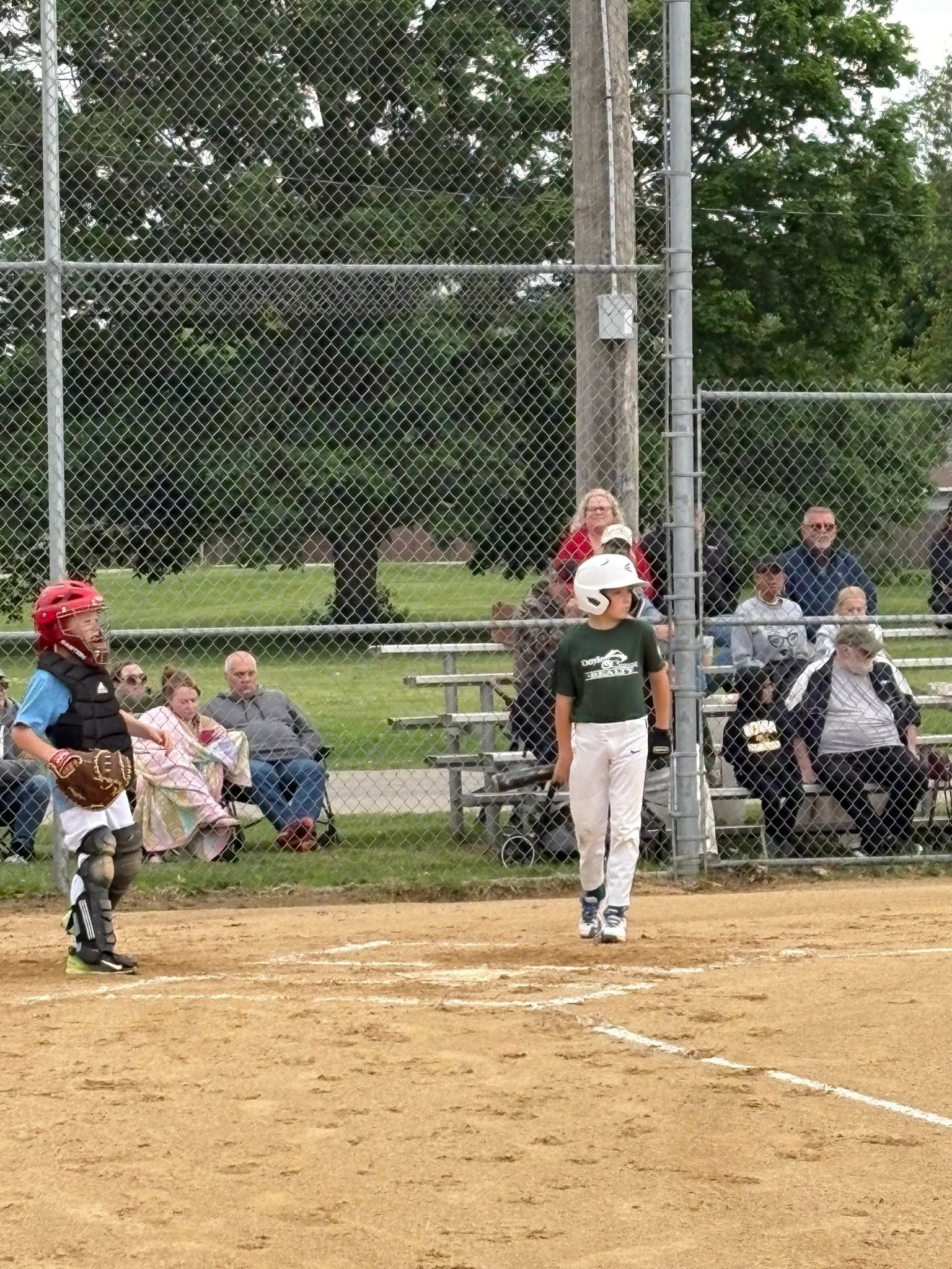 A player in a Doyle & Associates jersey walking to the batter's box