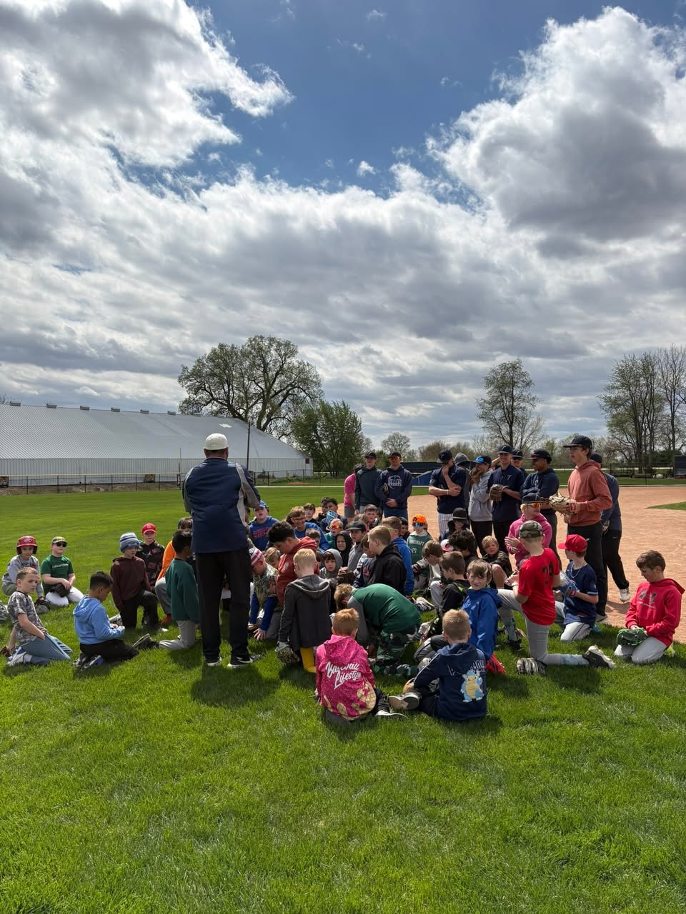 Coach leading a huddle with a large group of kids at a skills clinic