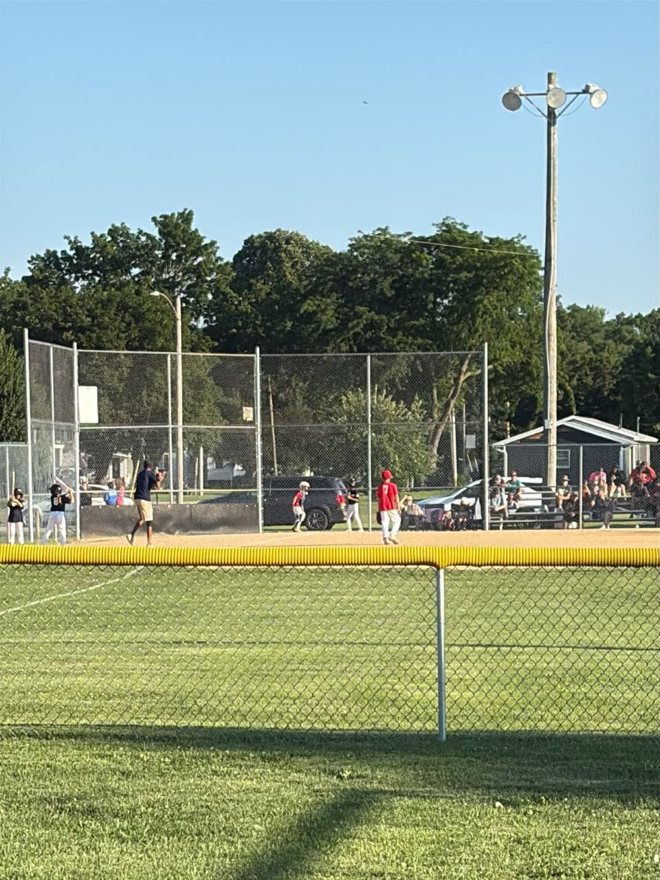 Wide shot of a game in progress with players on the field and spectators in the bleachers
