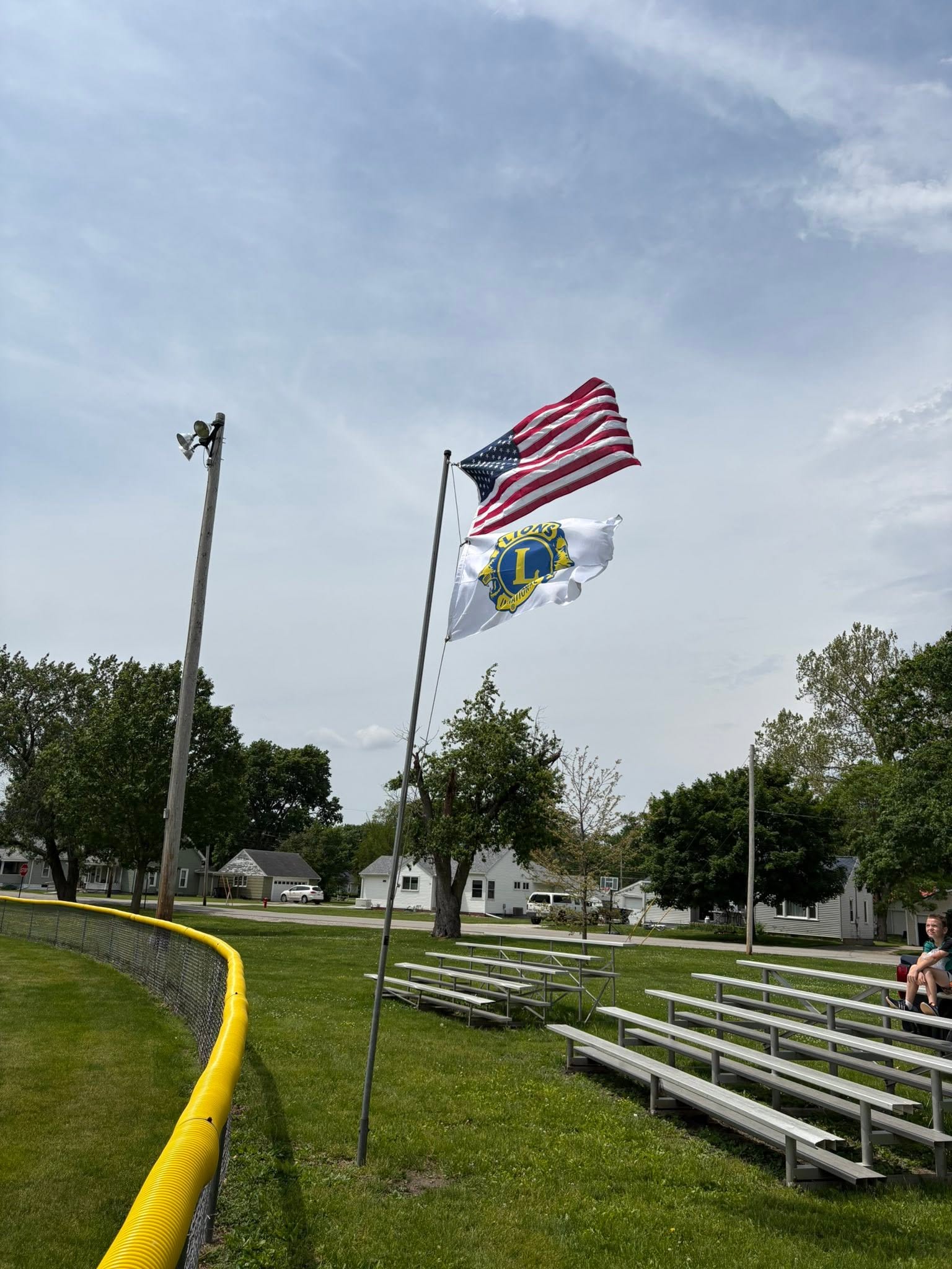 The American flag flying alongside the Lions Clubs International flag above the field