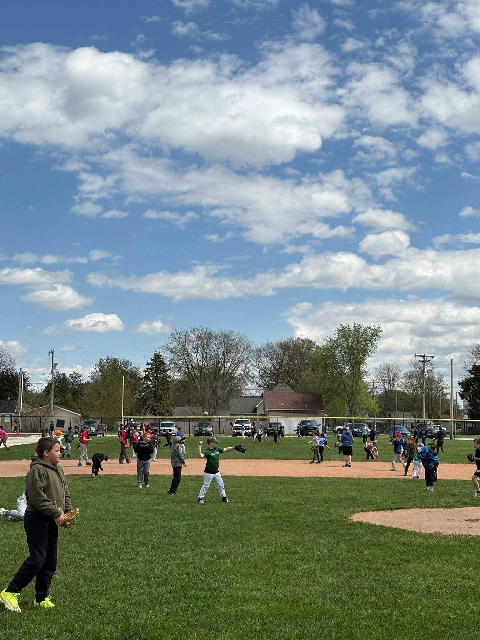 Wide shot of kids playing catch across the practice field